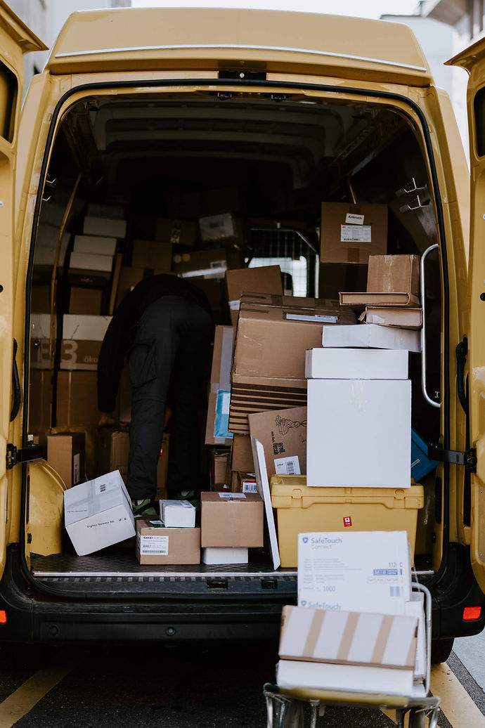 Back of carrier truck with parcels of mixed size. Choosing the right carrier for shipping large packages can reduce surcharges.