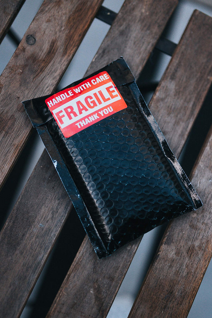 Black bubble mailer with red and white fragile sticker. 