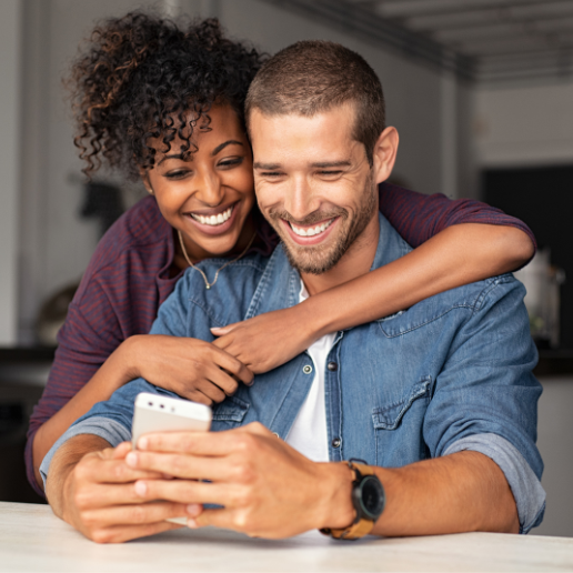 Couple hugging while man looks at his phone
